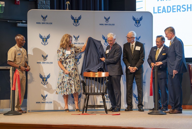 Several people revealing the new chair